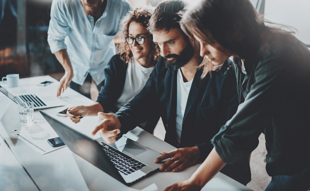 office workers standing around a laptop