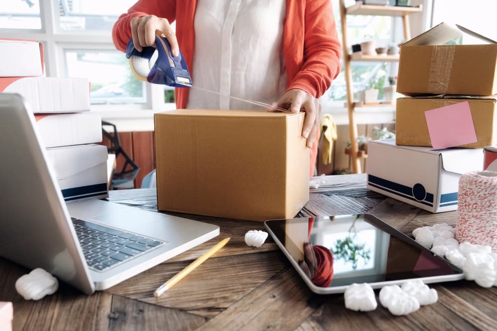 person taping up a box to ship