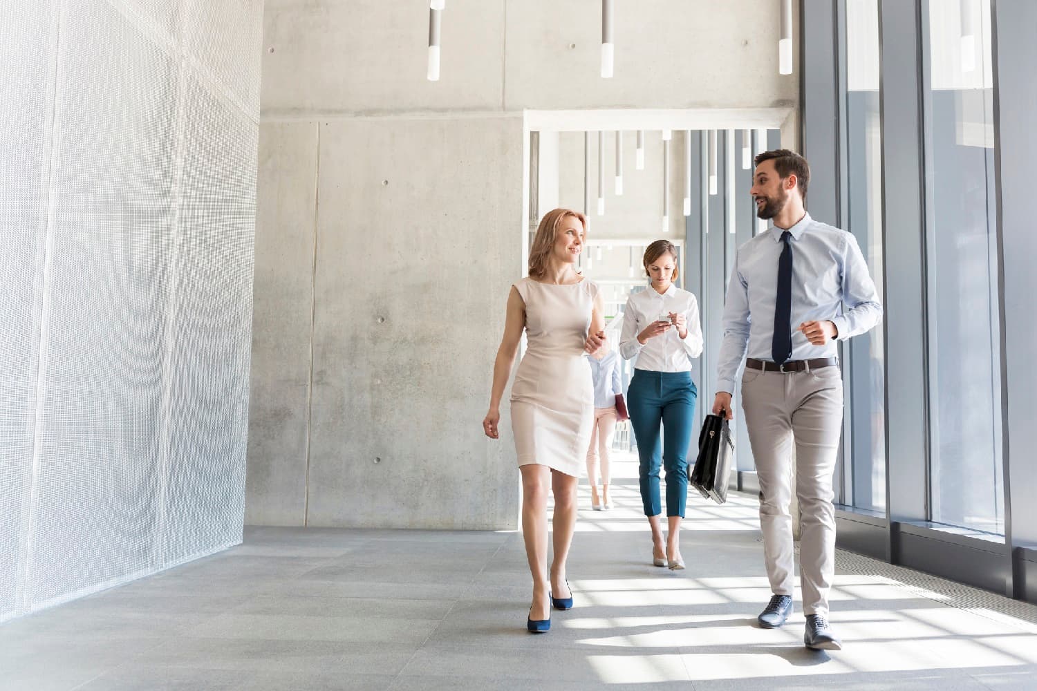 Colleagues chatting as they walk through an office hallway