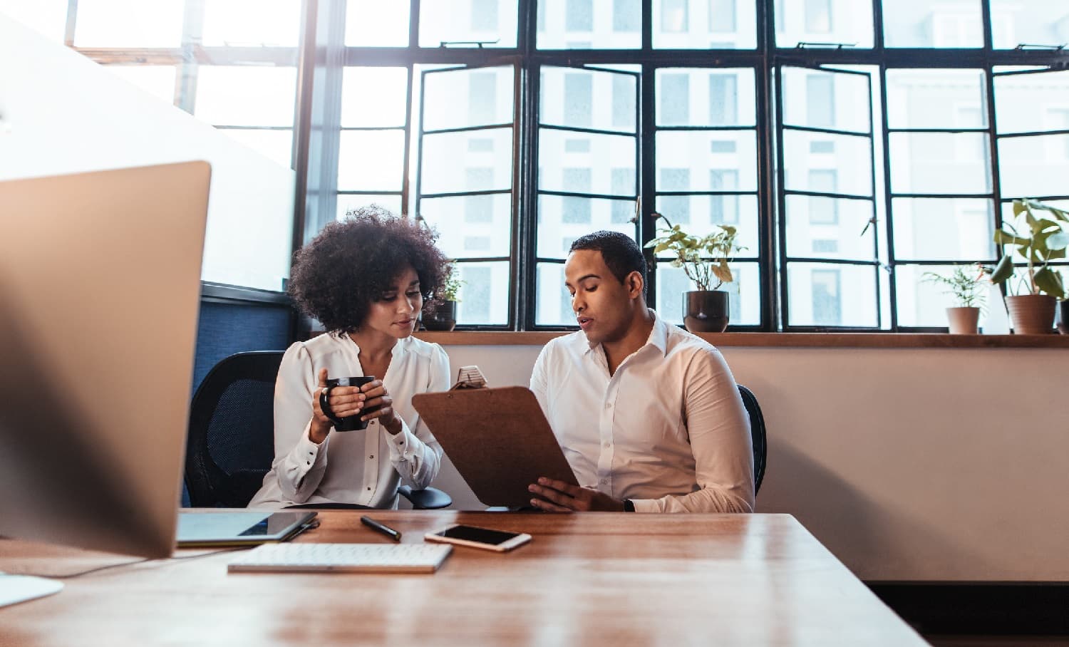 two business partners conversing at a desk